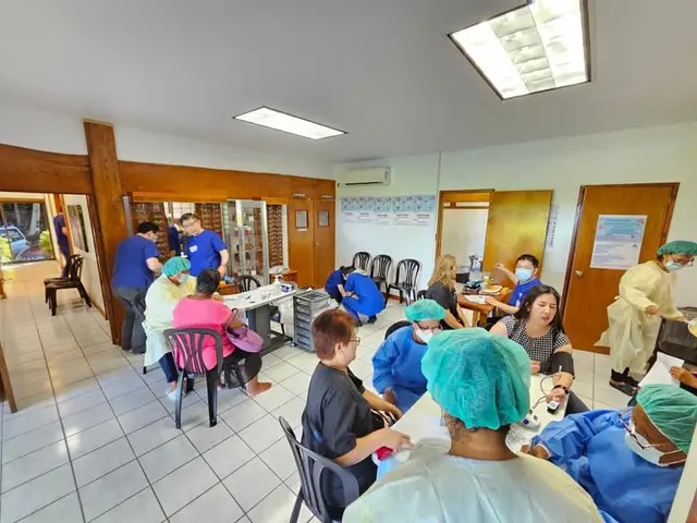 Volunteers at tables screening patients in a large clinic room