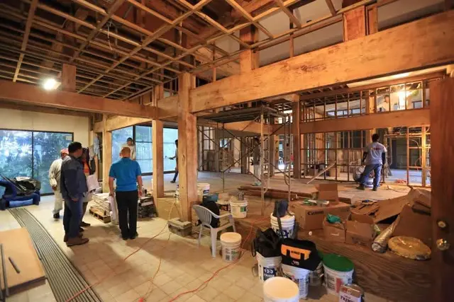 Clinic interior under renovation with exposed timber beams and workers