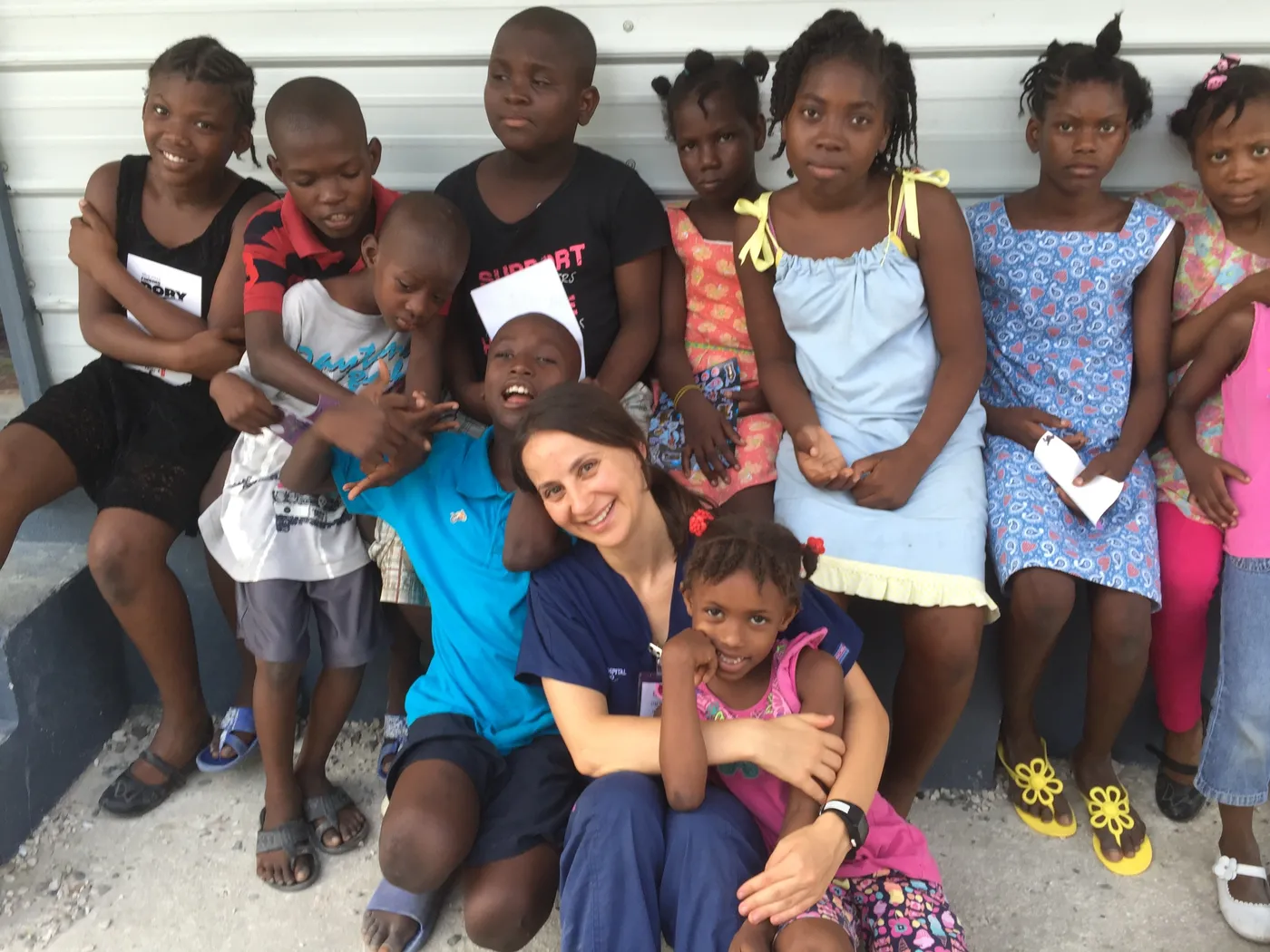 Elena Taneva sitting with a large group of smiling children from Haiti