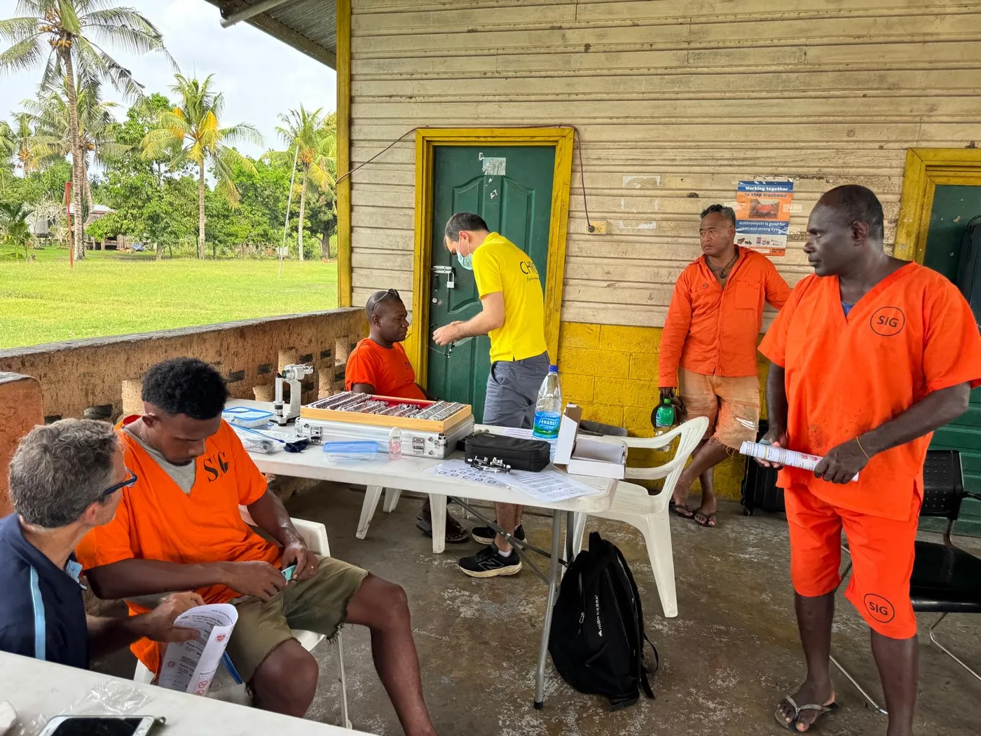 Eye clinic set up on a school veranda, with patients in orange shirts waiting to be seen